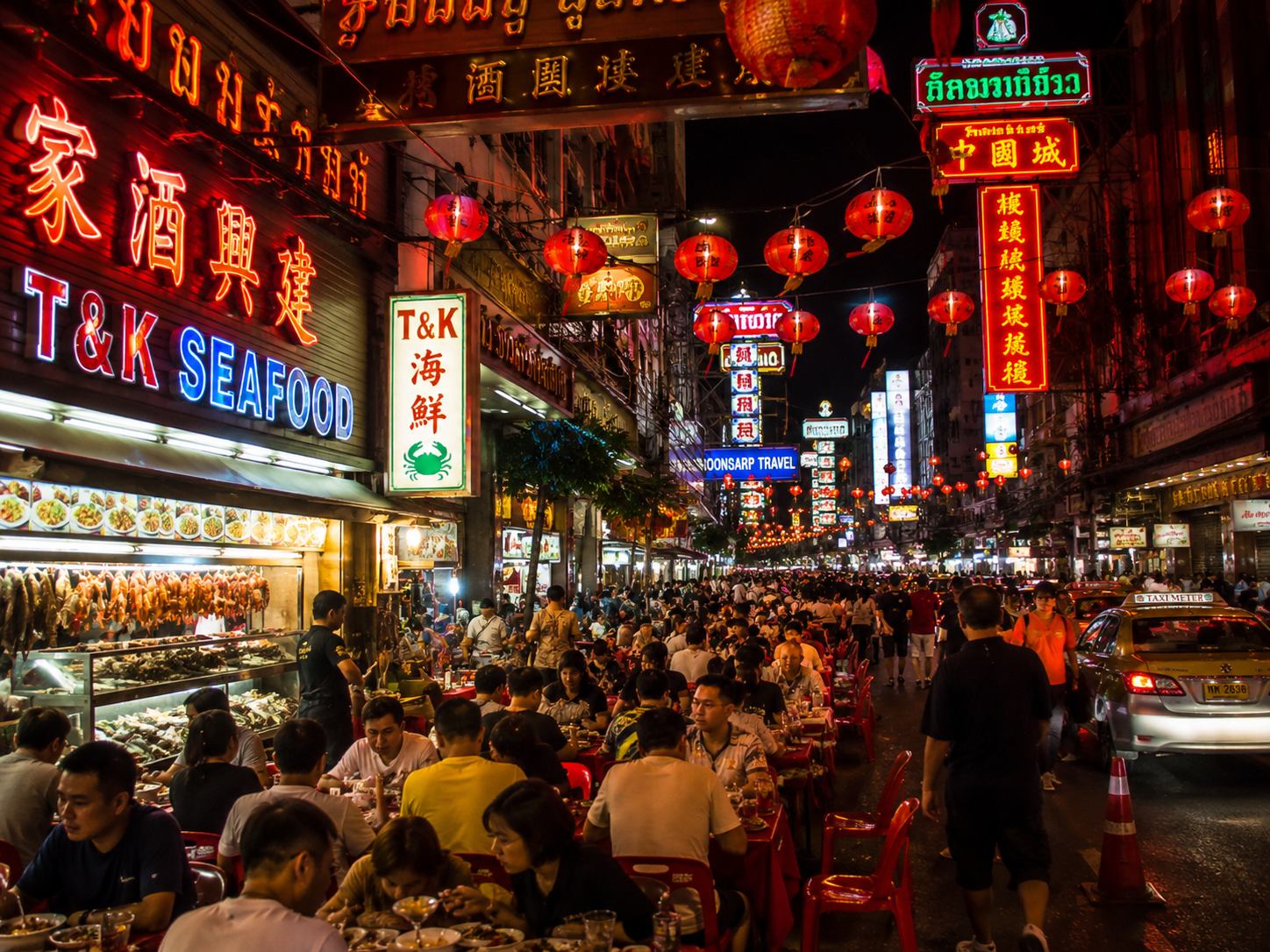 Yaowarat Road at night with neon signs, red lanterns, and street food stalls in Bangkok Chinatown